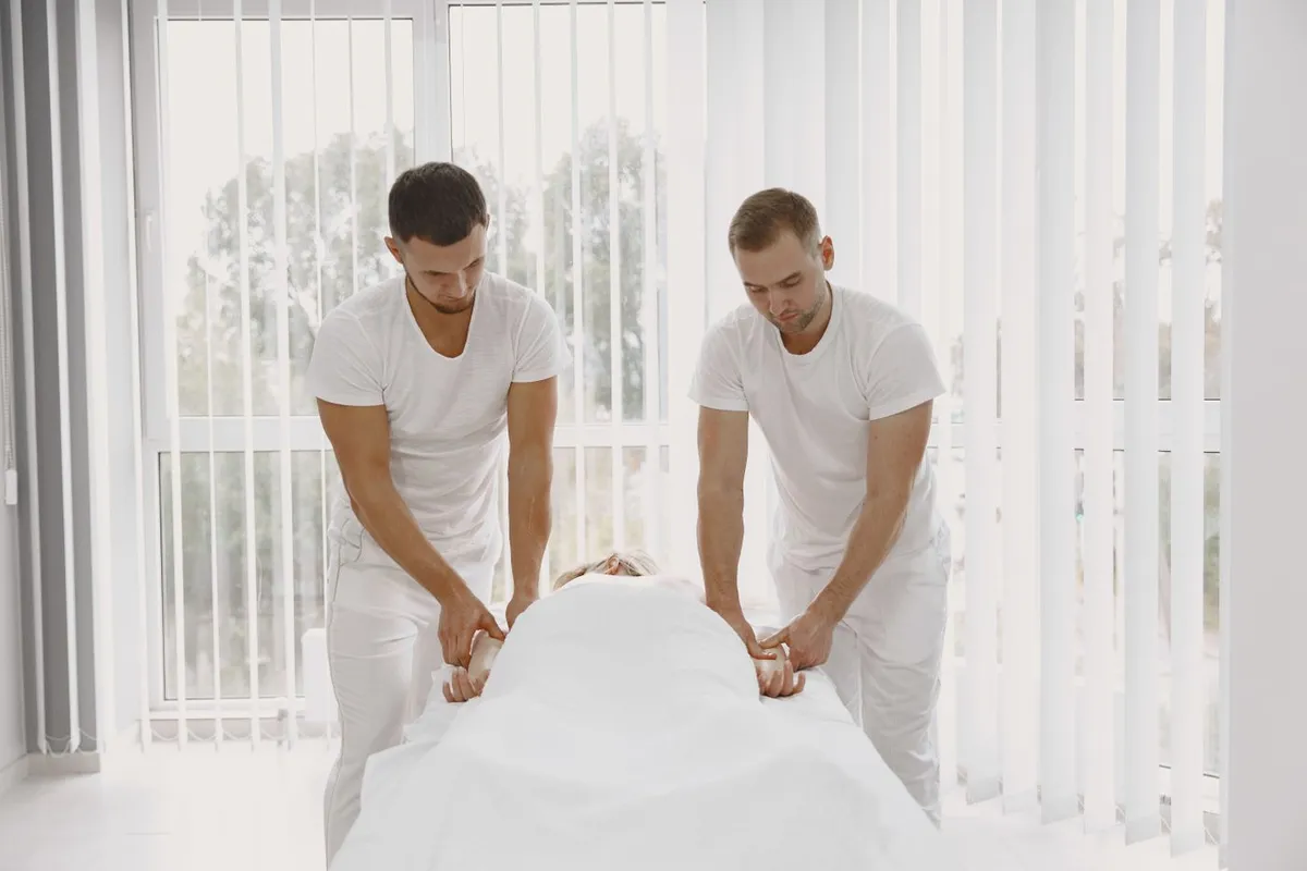 Two therapists performing a coordinated massage